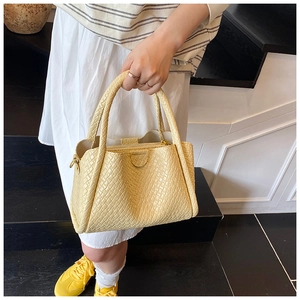 Détail du sac panier tressé jaune clair avec texture précise et bandoulière amovible