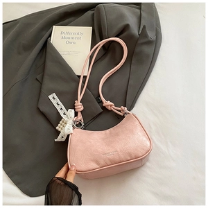 Close-up of light pink embossed hobo bag with white lace bow and pearl pendant details