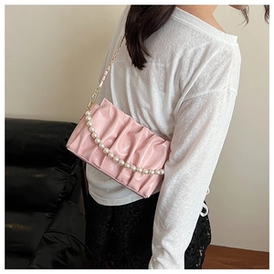 Gros plan du sac nuage plissé rose avec anse en perles et finition en cuir brillant