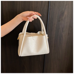 Détail du sac à main blanc cassé tressé avec crochets métalliques et fermeture éclair