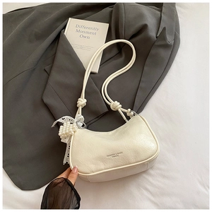 Detail of creamy white crescent bag featuring pleated PU leather and pearl lace charm
