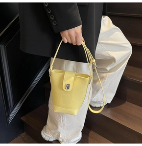 Detail of yellow bucket bag with lychee grain leather and silver buckle on the shoulder