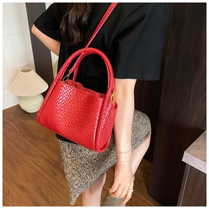 Détail du sac seau rouge tissé montrant la texture fine et les crochets dorés