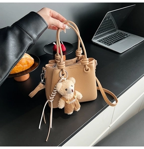 Close-up of beige lychee texture bucket bag with cute plush bear pendant accessory