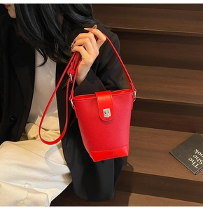 Detail of red lychee grain leather bucket bag featuring a silver metal square lock buckle