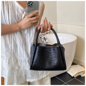 Détail du sac seau en cuir tressé noir avec plis souples et doubles anses rondes