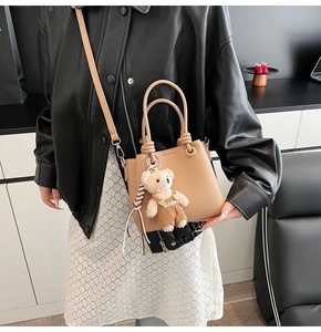 Close-up of caramel lychee texture bucket bag with knotted handle and plush bear charm