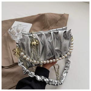 Détail du sac argenté plissé avec bandoulière en perles et boule métallique dorée