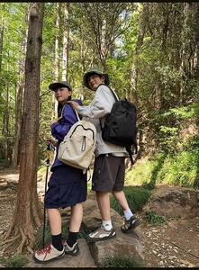 Waterproof nylon backpack shown in a forest setting with a trekking pole and hiking gear