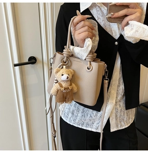 Detail of lychee pattern leather bucket bag with cute teddy bear charm and knotted handle