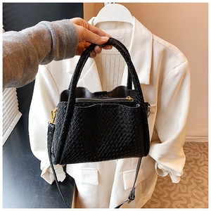 Détail de la texture tressée noire et de la bandoulière amovible du sac à main seau