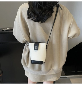 Detail of mini bucket bag in black and white lychee leather worn by a model