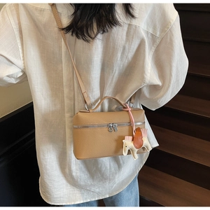 Dettaglio borsa box in pelle litchi kaki indossata a tracolla su una camicia di lino bianco