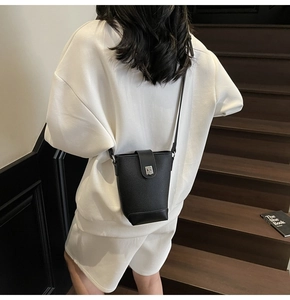 Detail view of black lychee grain leather bucket bag with silver metal clasp on model
