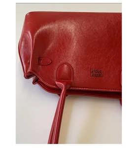 Gros plan sur sac en cuir ciré rouge montrant la texture brillante et logo gravé