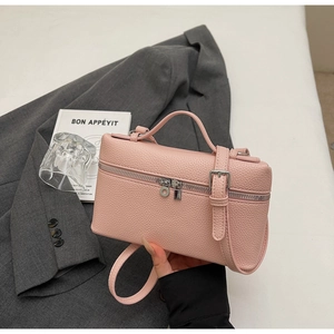 Dettaglio della borsa rosa con trama in pelle litchi, doppia cerniera e manico superiore