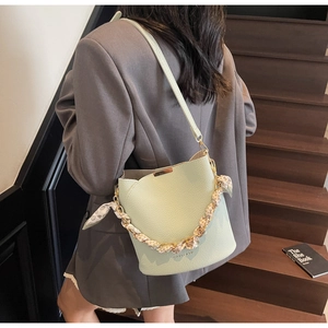 Detail view of light green pebble leather bucket bag with silk scarf chain handle and strap