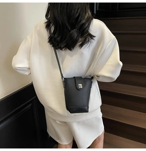 Detail view of black litchi grain leather bucket bag with silver metal square lock buckle