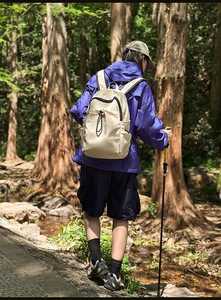 Waterproof cream backpack for hiking and commuting shown in outdoor forest scenery