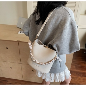 Close-up of cream bucket bag showing lychee texture and silk scarf metal chain