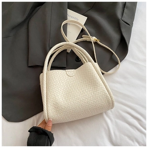Détail d'un sac seau tressé blanc montrant la texture du cuir et la bandoulière réglable