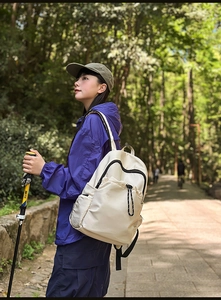 Off-white waterproof nylon hiking backpack with pockets shown in outdoor forest setting