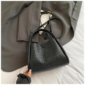 Détail du sac seau en cuir tressé noir avec ferrures dorées et bandoulière réglable