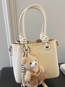 Minimalist cream lychee grain bucket bag with knotted handle and teddy bear charm