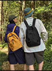 Waterproof nylon backpacks in yellow and black shown in a scenic outdoor forest setting
