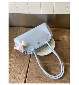 Détail du sac à bandoulière en cuir bleu clair avec gaufrage COOL KIDS et breloque