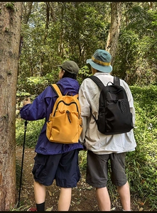 Detail of lightweight waterproof nylon backpacks in yellow and black during a forest hike
