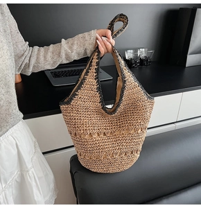 Close-up of woven straw tote bag with black trim detailing and hollow knit design