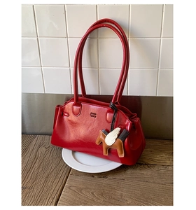 Détail du sac bowling en cuir verni rouge avec gaufrage de marque et pendentif pégase