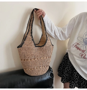Close-up of hollow woven detail and black crochet handles on straw beach tote bag