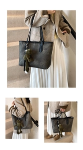 Detail of a large dark grey tote bag with a green frog plush charm and black straps