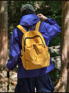 Waterproof yellow nylon backpack detail showing front drawstring pocket and side mesh pocket