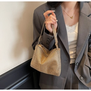 Gros plan d'un sac à main scintillant en maille de strass dorés tenu par un mannequin