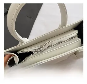 Detailed close-up of premium silver zipper and stitching on a white leather handbag
