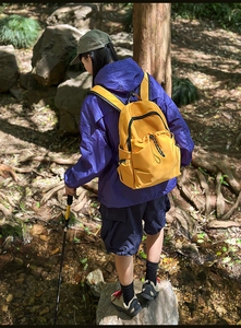 Outdoor yellow nylon backpack shown in forest setting with waterproof multi-pocket design