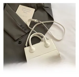 Detailed macro shot of white faux leather handbag with embossed letters on a suit jacket