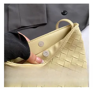 Dettaglio della fibbia magnetica sulla borsa a secchiello intrecciata beige con metallo
