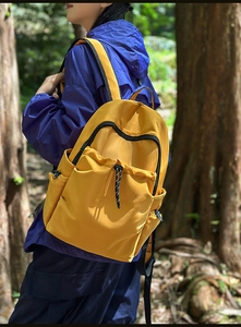 Outdoor side view of ginger waterproof nylon backpack with multi-pocket design and drawstrings