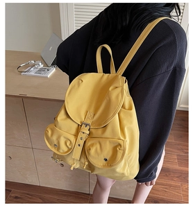 Détail d'un sac à dos en toile jaune moutarde avec doubles poches et boucles en métal