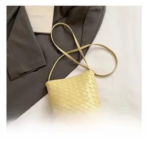 Dettaglio della borsa a secchiello giallo chiaro con trama in pelle intrecciata di lusso