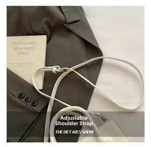 Detailed view of the white leather handbag with an adjustable strap and silver metal buckle