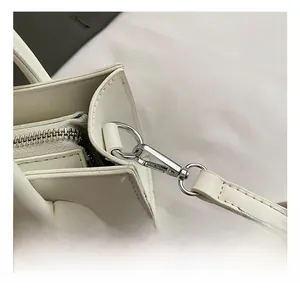 Close-up of premium silver metal hook and fine stitching on white leather handbag