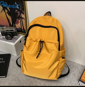 Close-up of a yellow waterproof backpack with front drawstring pocket and black zippers