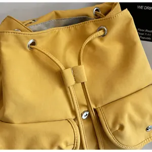 Détail du sac à dos en toile jaune vif avec fermeture à cordon et poches à rabat magnétique