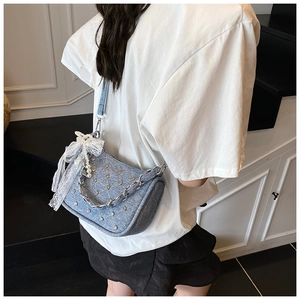 Détail du sac à bandoulière en jean bleu clair avec strass argentés et nœud en dentelle