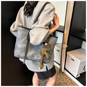 Detail of grey marble pattern tote bag with black leather trim and plush charm